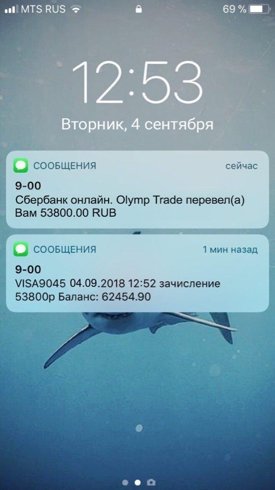 экран телефона с уведомлением о зачислении денег на фоне ноутбука с открытым сайтом Авито